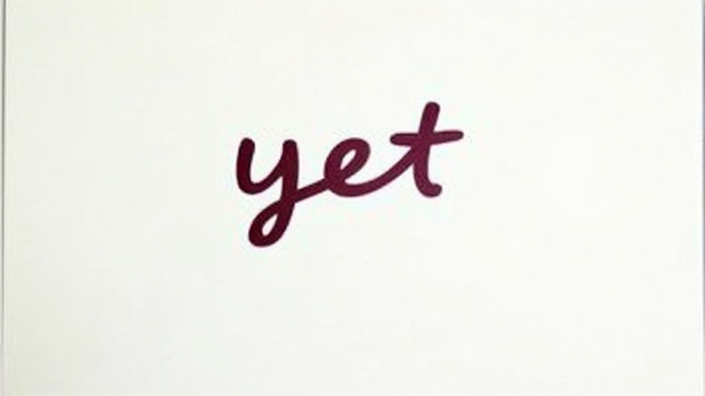 A simple notepad with the word 'yet' written in a playful, flowing script with a bright, open background. No humans or additional text.